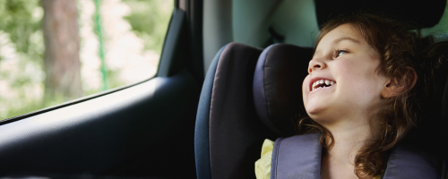 Traveling with Kids - Helpful Tips Kind im Kindersitz im Auto schaut aus Fenster